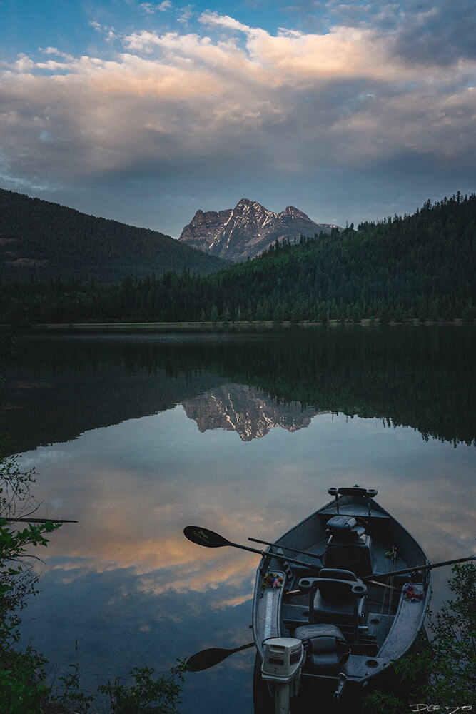 A row boat on Bad Medicine Lake looking out towards a mountain at dusk, Montana